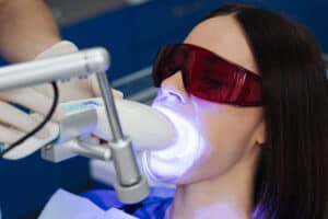 A woman has a teeth whitening procedure with OptiSmile, showcasing professional care.
