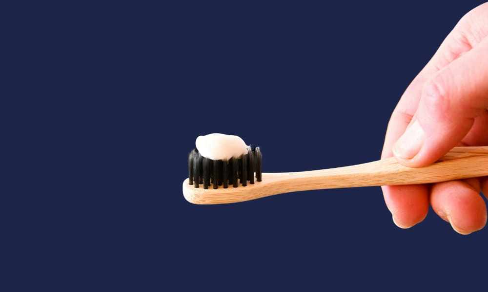 A hand holding a toothbrush with fluoride toothpaste