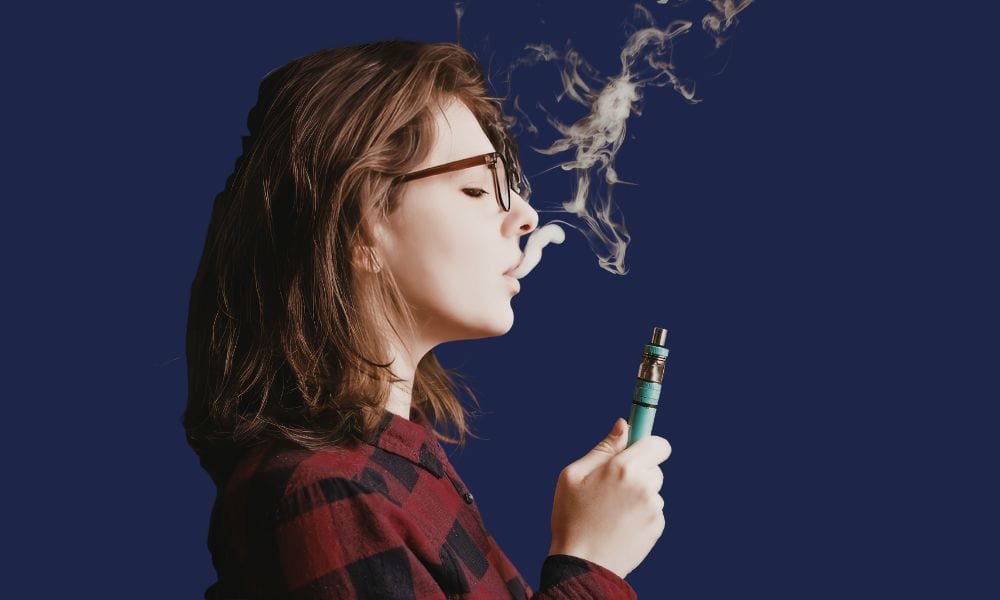 Woman vaping with an e-cigarette — vaping vs smoking and the effects on oral health