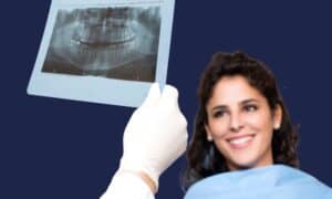 Patient smiling whilst a dentist holds up a panoramic dental x-ray for review during a co-discovery consultation